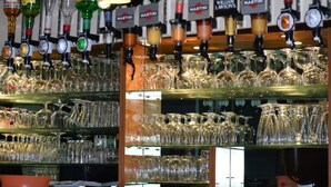 Een bar met verschillende drankkranen en planken vol met divers servies.