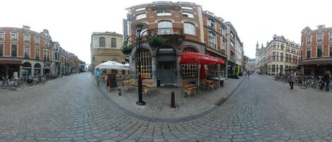 Una calle adoquinada con un café llamado "Pim's O'Clock" y una librería.