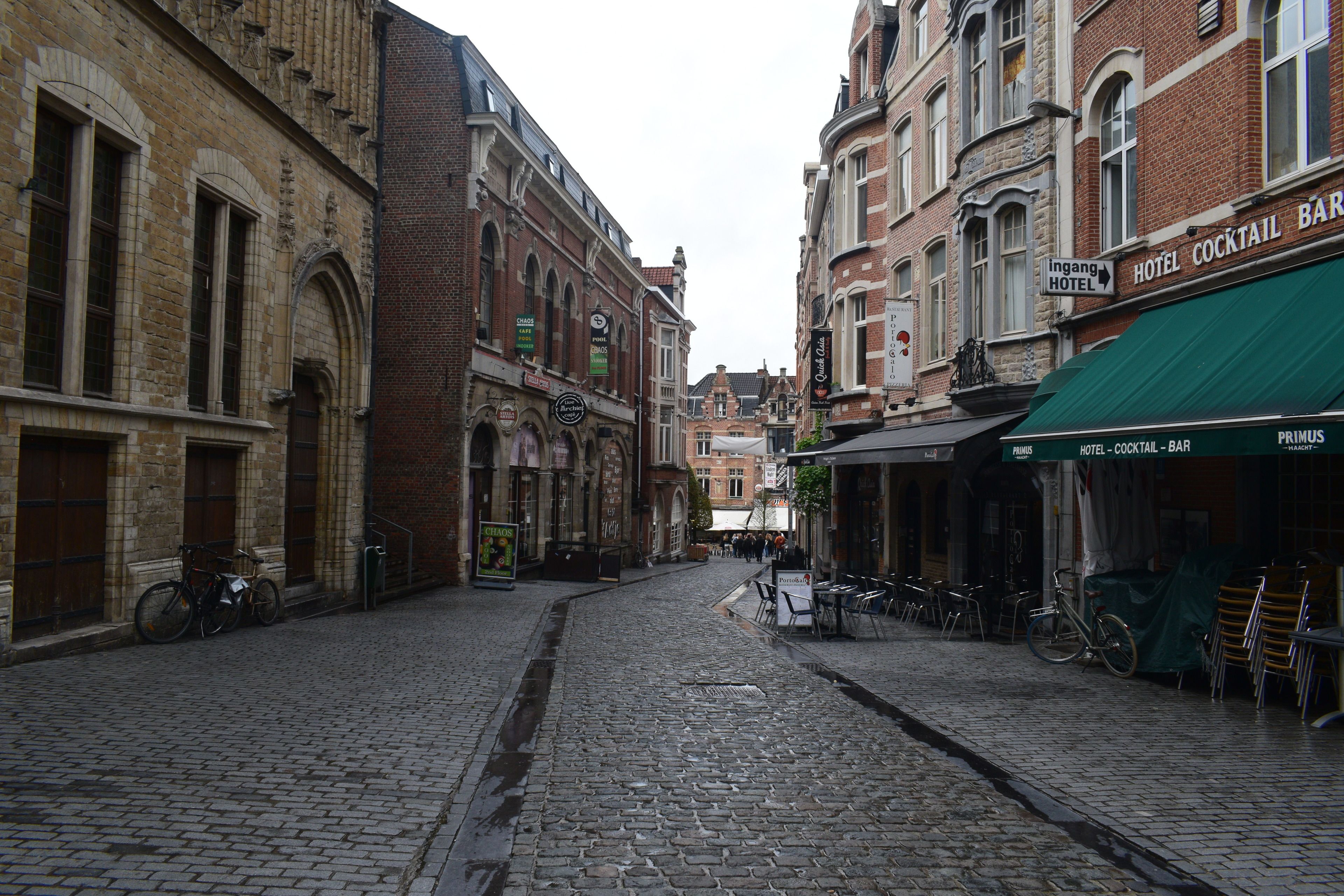 A cobblestone street lined with historic buildings, including a hotel with a green awning.