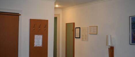 Habitación de hotel con puerta de madera, un espejo, una cama con cabecera y una lámpara fijada a la pared.