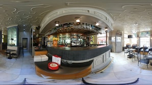 Een bar met een gebogen toonbank, meerdere biertappunten en een zithoek met tafels en stoelen.