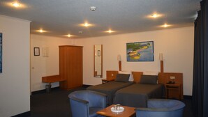 Een hotelkamer met twee enkele bedden, een bureau, een stoel en een klein tafeltje met een dienblad.