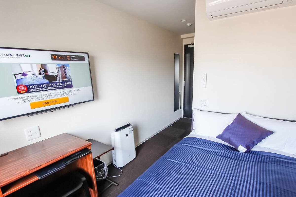 Quarto de hotel com cama, escrivaninha, cadeira, televisão e aquecedor.