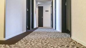 A hotel hallway with carpeted flooring, doors on both sides, and a sign on the wall. - HOTEL LiVEMAX Kyoto Nijojo-kita (Kyoto)
