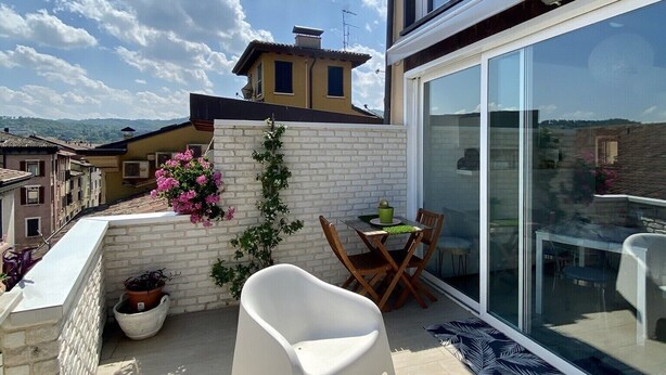 A modern balcony with a glass door, white chairs, and a table with a potted plant. - Angelina's house (Salò)