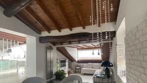 A dining area with a table set for four, a sofa, and a TV in the background. - Angelina's house (Salò)