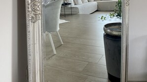 A modern living room with a large mirror, a white sofa, a black chair, and a large potted plant. - Angelina's house (Salò)