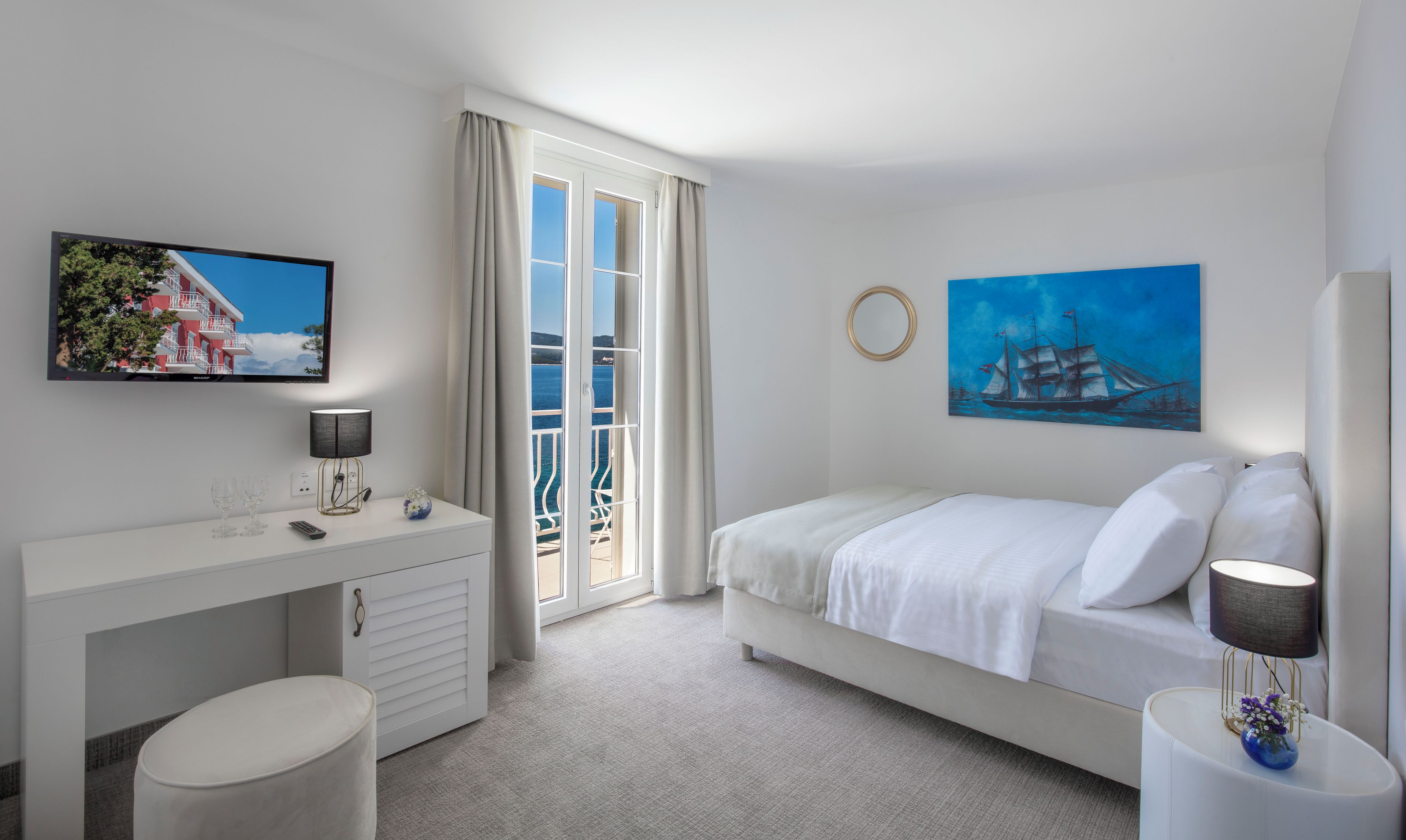 Una habitación de hotel con una cama, un escritorio con lámpara, un televisor y un cuadro.