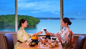 Una mesa de comedor con diversos platos y bebidas, con vistas a un paisaje de un lago y vegetación.