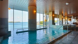 Una piscina interior con vistas despejadas al mar, grandes ventanales y un diseño arquitectónico moderno.