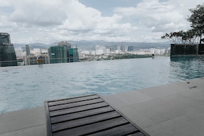 An infinity pool with a cityscape view, including high-rise buildings and mountains in the background.