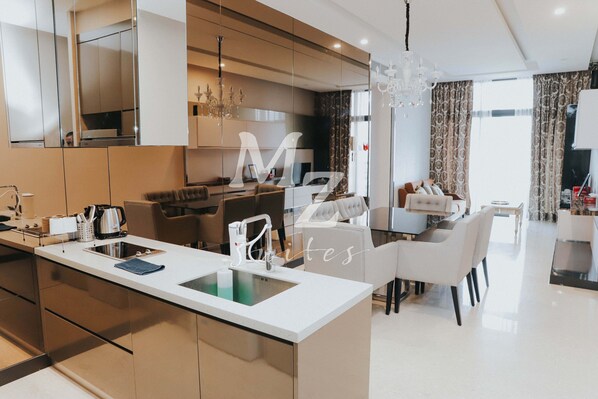 A modern kitchen with a central island, a dining area with white furniture, and a large mirror reflecting the space.