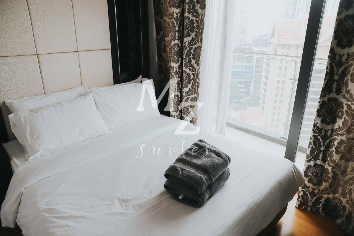 Ein Hotelzimmer mit Bett, weißer Bettwäsche und einem Fenster mit Vorhängen.