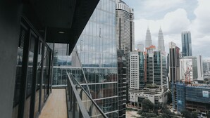 Un hôtel moderne doté d’une façade en verre, d’un balcon et offrant une vue sur les gratte-ciel environnants.