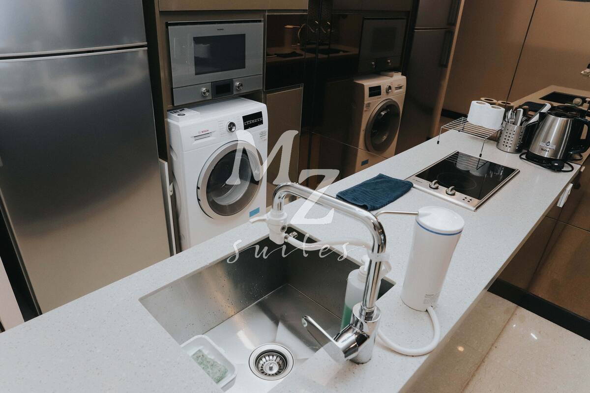 Eine moderne Küche mit Edelstahlgeräten, einer integrierten Waschmaschine und einer Kaffeemaschine.