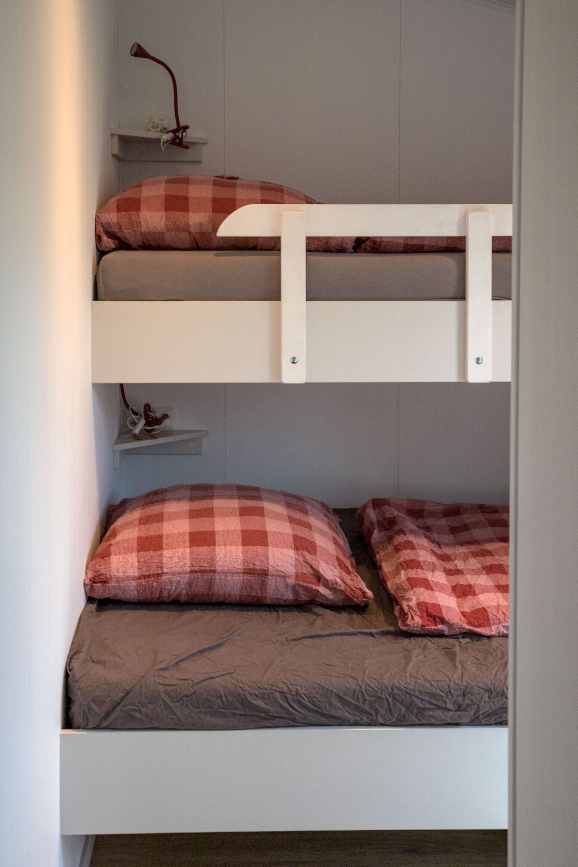 Una cama litera con dos niveles, cada uno con almohada y manta.