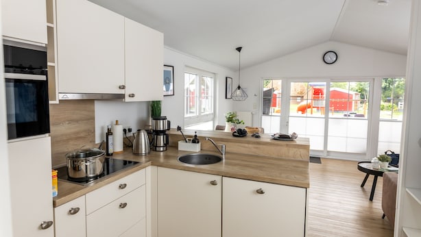 A modern kitchen with white cabinets, a wooden countertop, and a built-in stove. - Ferienhof Schild (Wangerland)