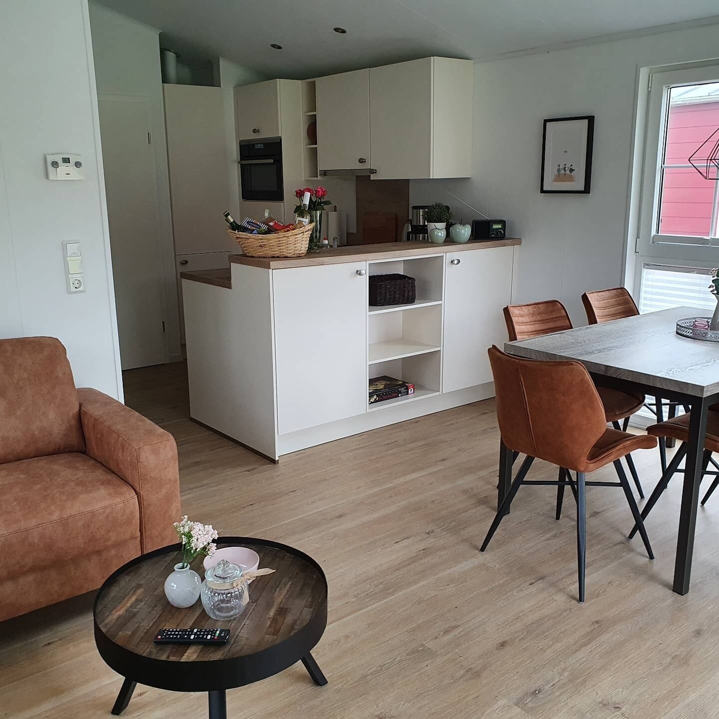 A modern kitchen with white cabinets, a dining table with chairs, and a round coffee table with a remote control.