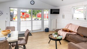 A spacious living area with a dining table, brown sofa, and a television mounted on the wall. - Ferienhof Schild (Wangerland)