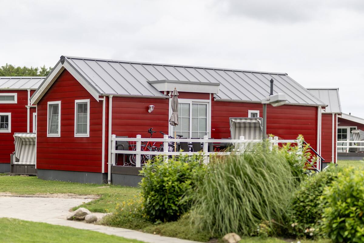 A red building with white trim, a white fence, and a pathway leading to the entrance.