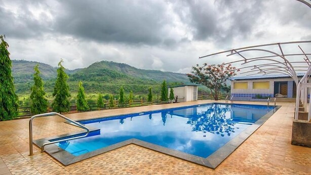 A swimming pool with a view of mountains and trees. - Dreammland Resort (Shahapur)