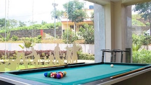 A pool table with balls and cues, set against a backdrop of a garden and a building. - Dreammland Resort (Shahapur)