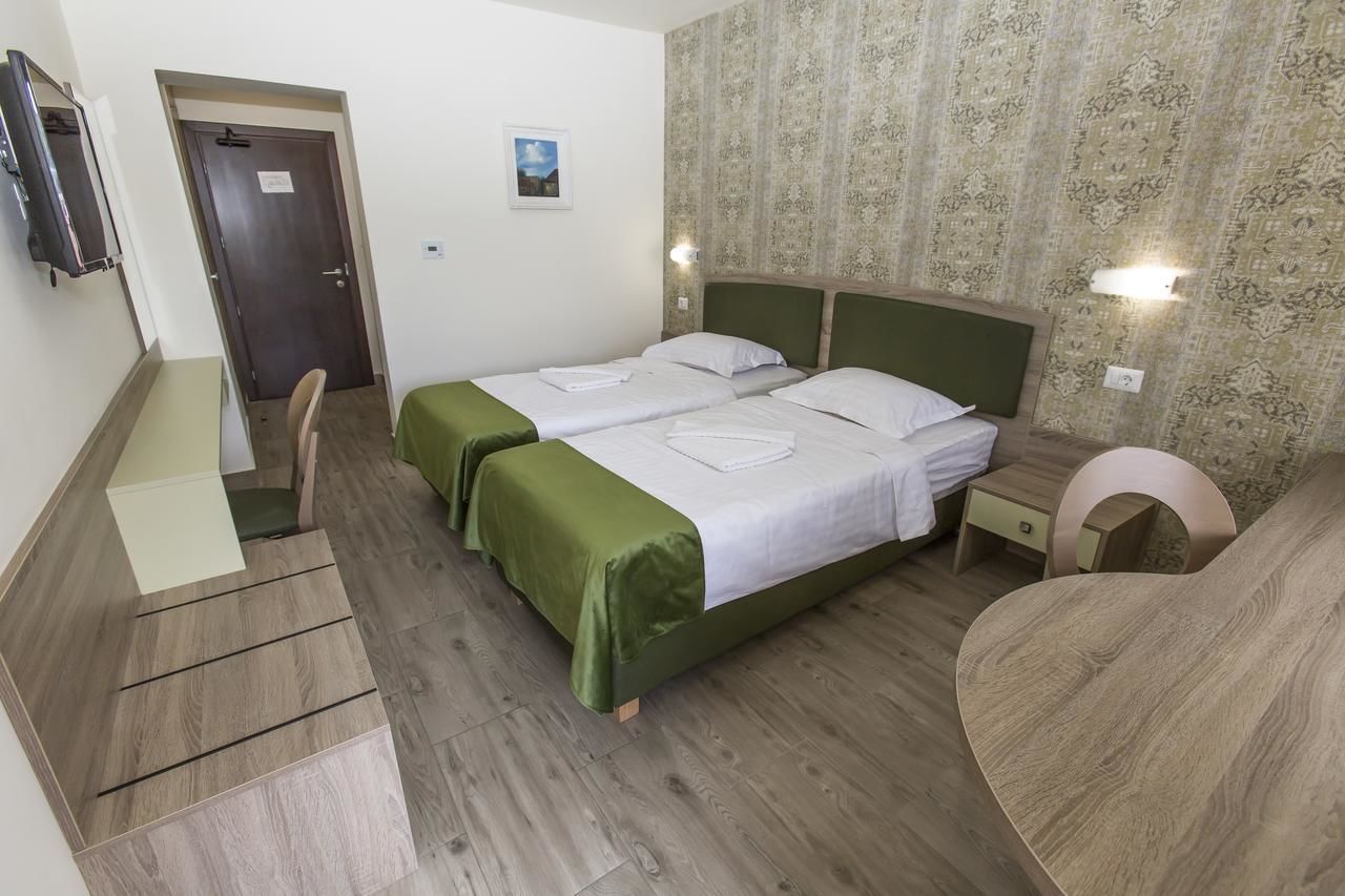 Una habitación con dos camas, un escritorio, una silla y una puerta.