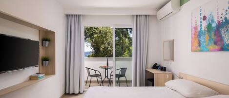 Habitación de hotel con cama, escritorio, silla, televisor y ventana con cortinas.