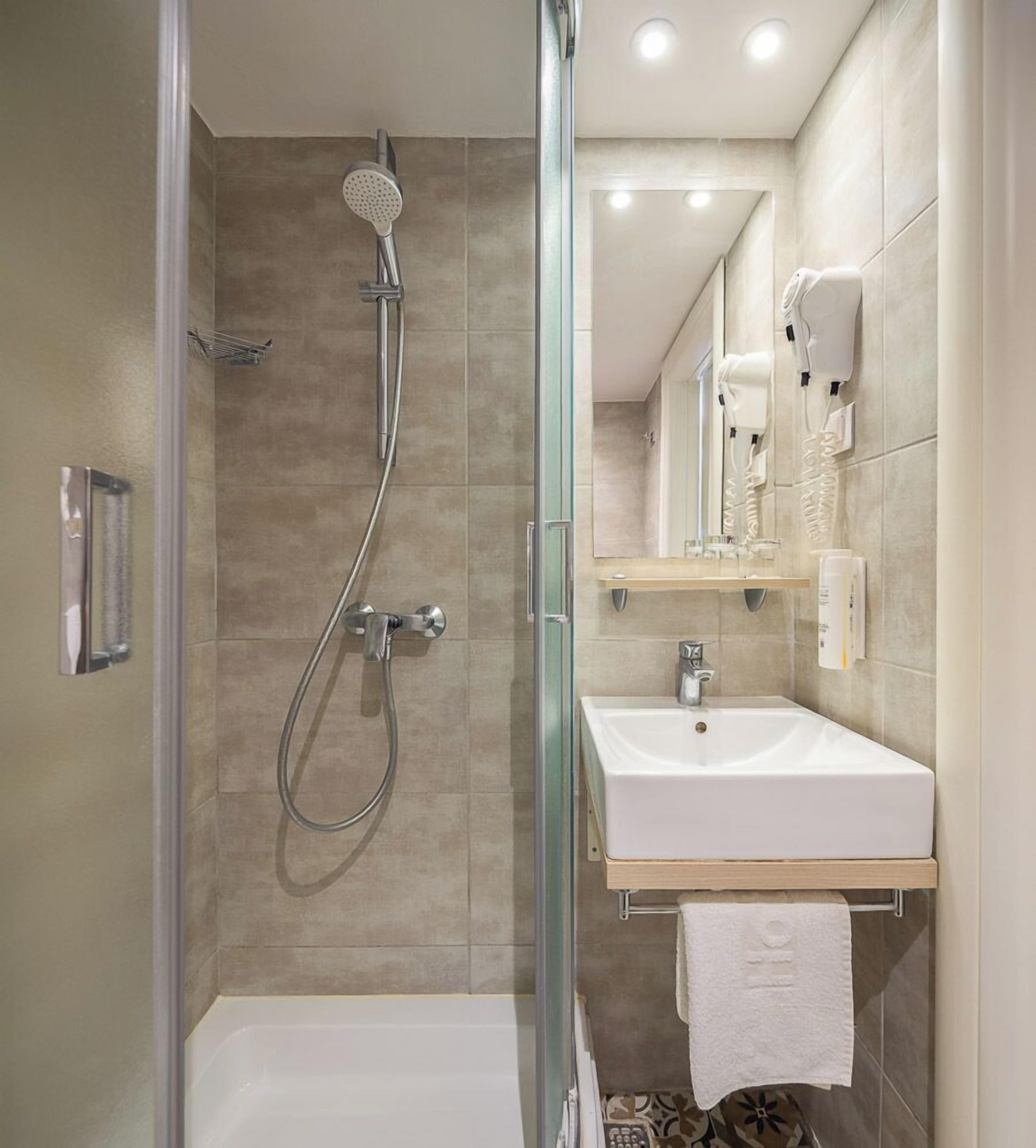 A modern bathroom with a glass-enclosed shower, a white sink, and a mirror above the sink.
