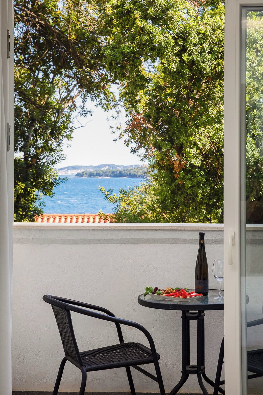 En balkon med et bord, en stol, en flaske og et glas.