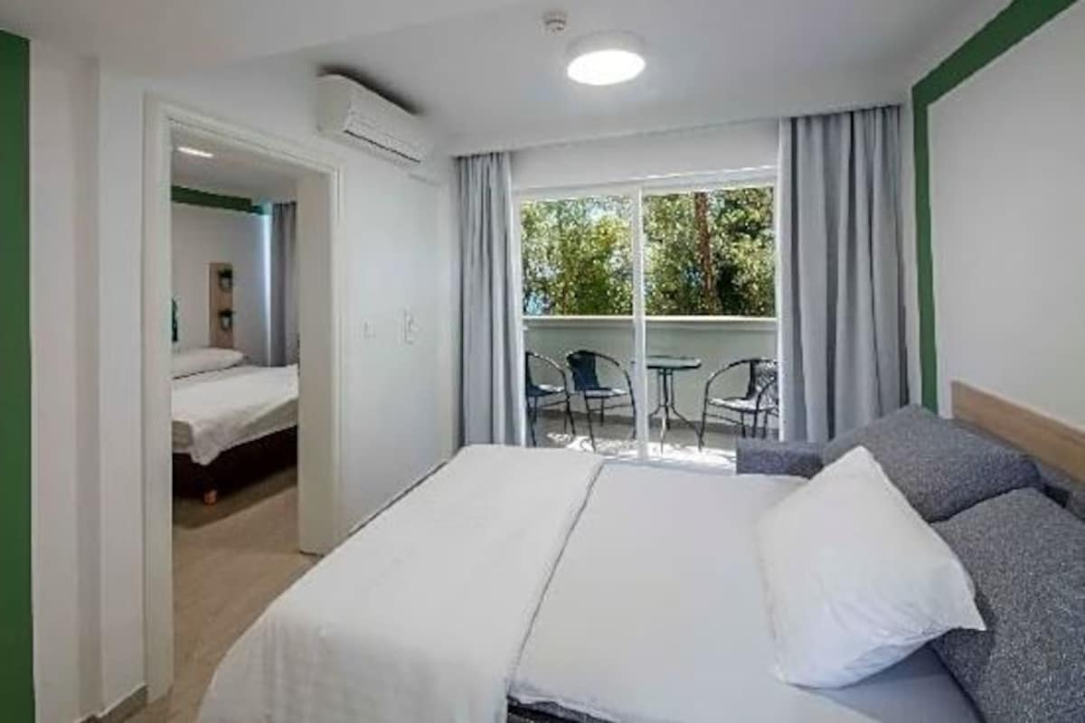Una habitación de hotel con una cama, una mesita y vistas al exterior.