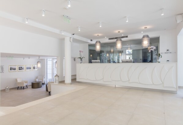 Un hall espacioso con mostrador de recepción, zona de estar e iluminación moderna.