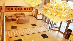 A lobby with a large chandelier, sofas, and a patterned rug. - Nooh Tower (Hidd)