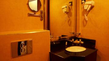 A bathroom with a round mirror, a hairdryer, and a sink.
