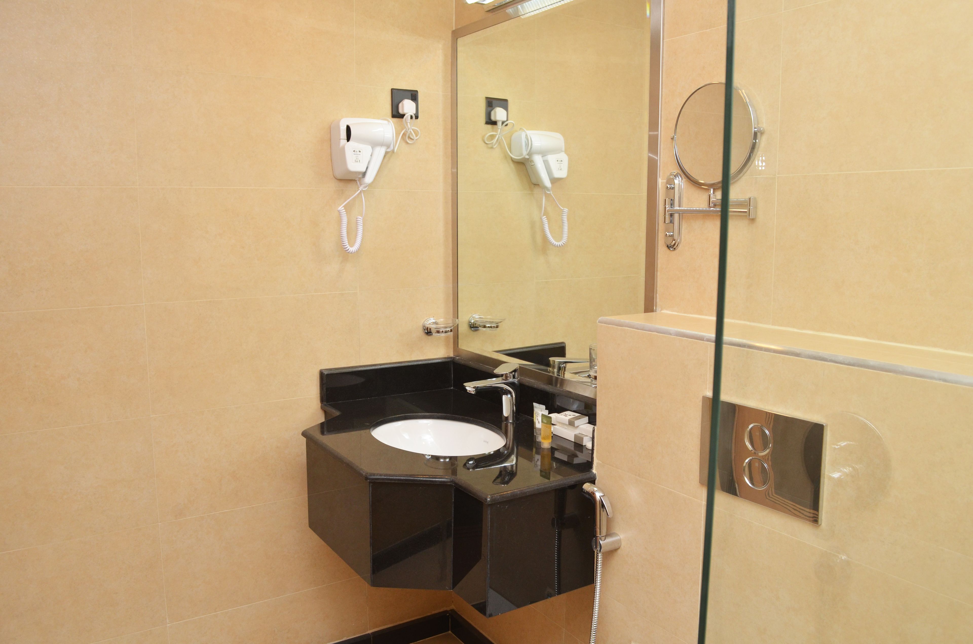 Un baño con un lavabo negro, un espejo y un secador de pelo montado en la pared.