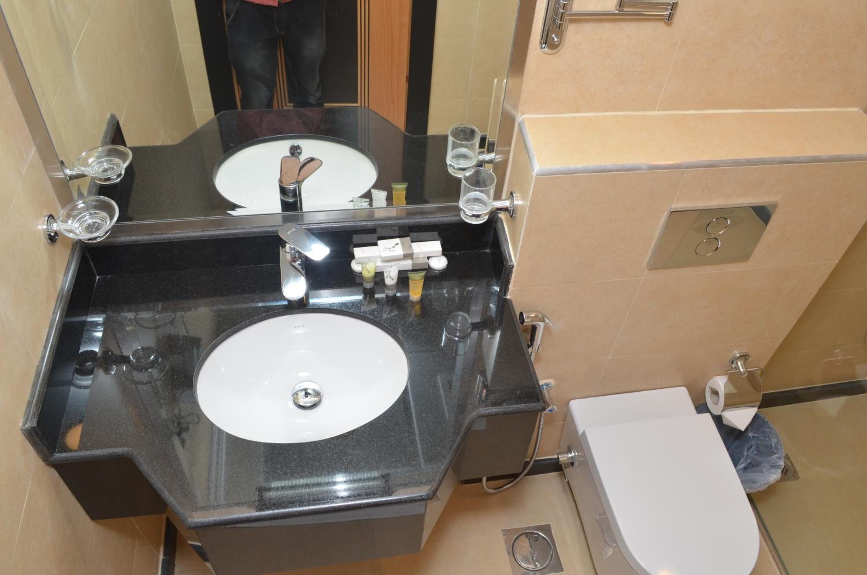 A bathroom with a black countertop, two sinks, and a toilet.
