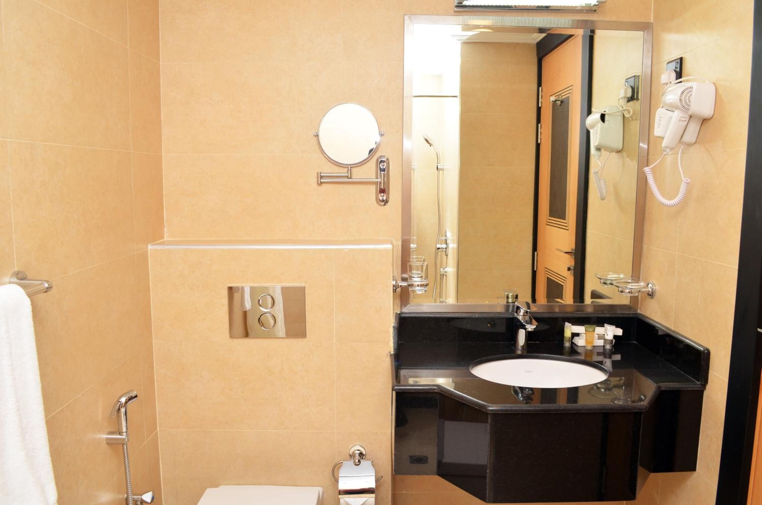 A modern bathroom with a black sink, a mirror, a hairdryer, and a shower.