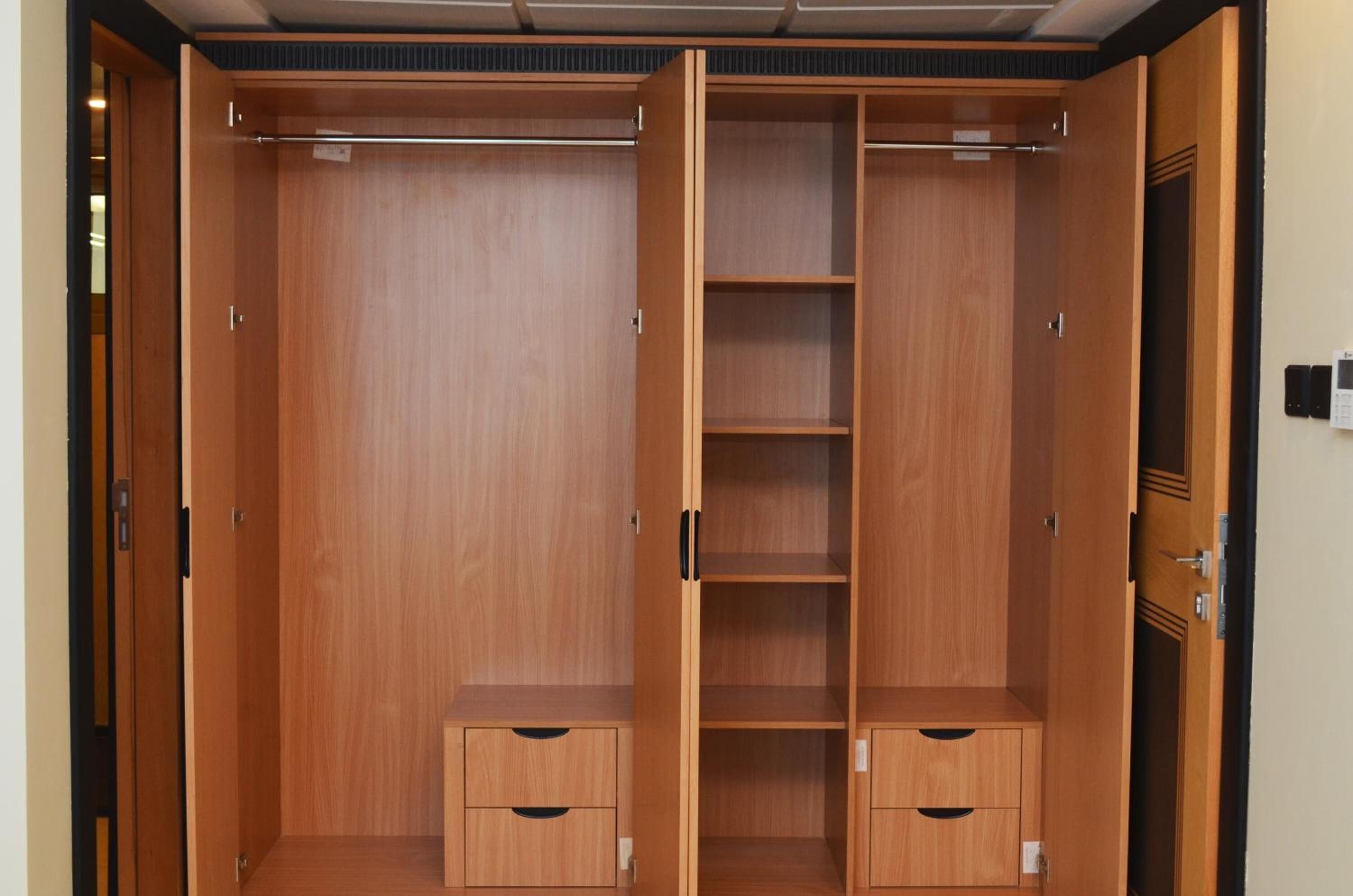 A wooden wardrobe with multiple compartments and a hanging rod.