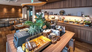 Zona de buffet con una variedad de alimentos, entre ellos frutas, verduras y productos de panadería. También hay varias cestas y recipientes para servir la comida.