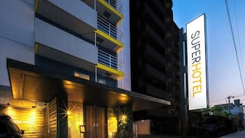A modern hotel with a prominent 'Superhotel' sign, multiple floors, and a well-lit entrance.