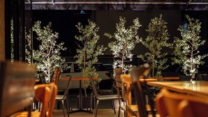 Un restaurante con mesas y sillas de madera, y varias plantas en macetas.