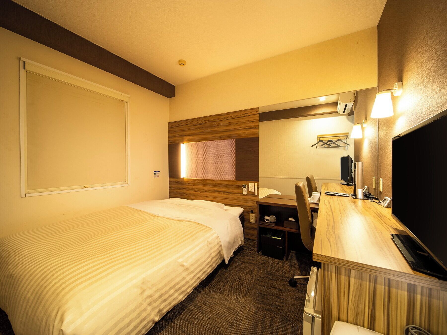 Une chambre d’hôtel avec deux lits, un bureau avec une chaise, une télévision et un miroir.