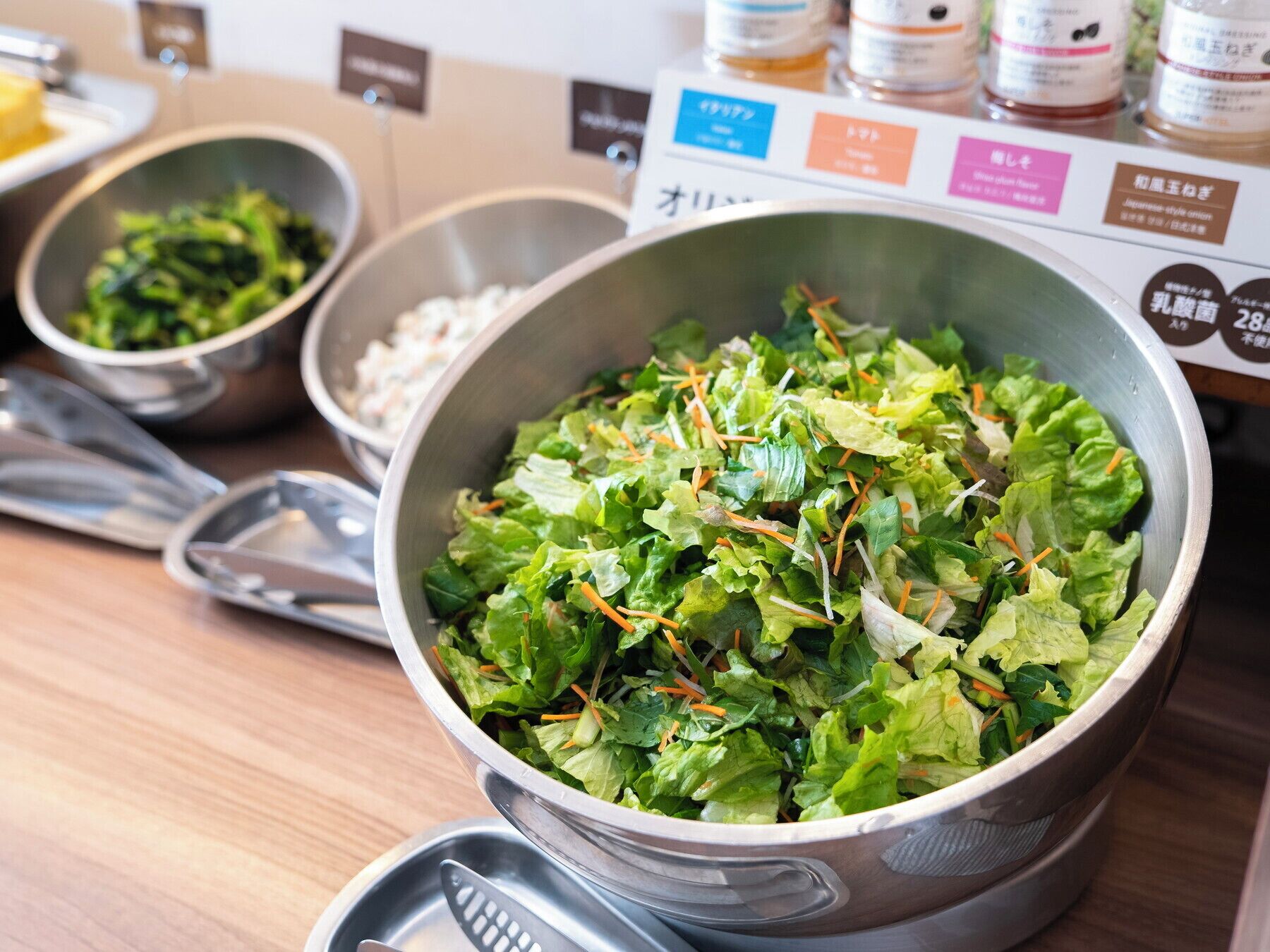 A salad bowl with mixed greens and shredded carrots on a table.