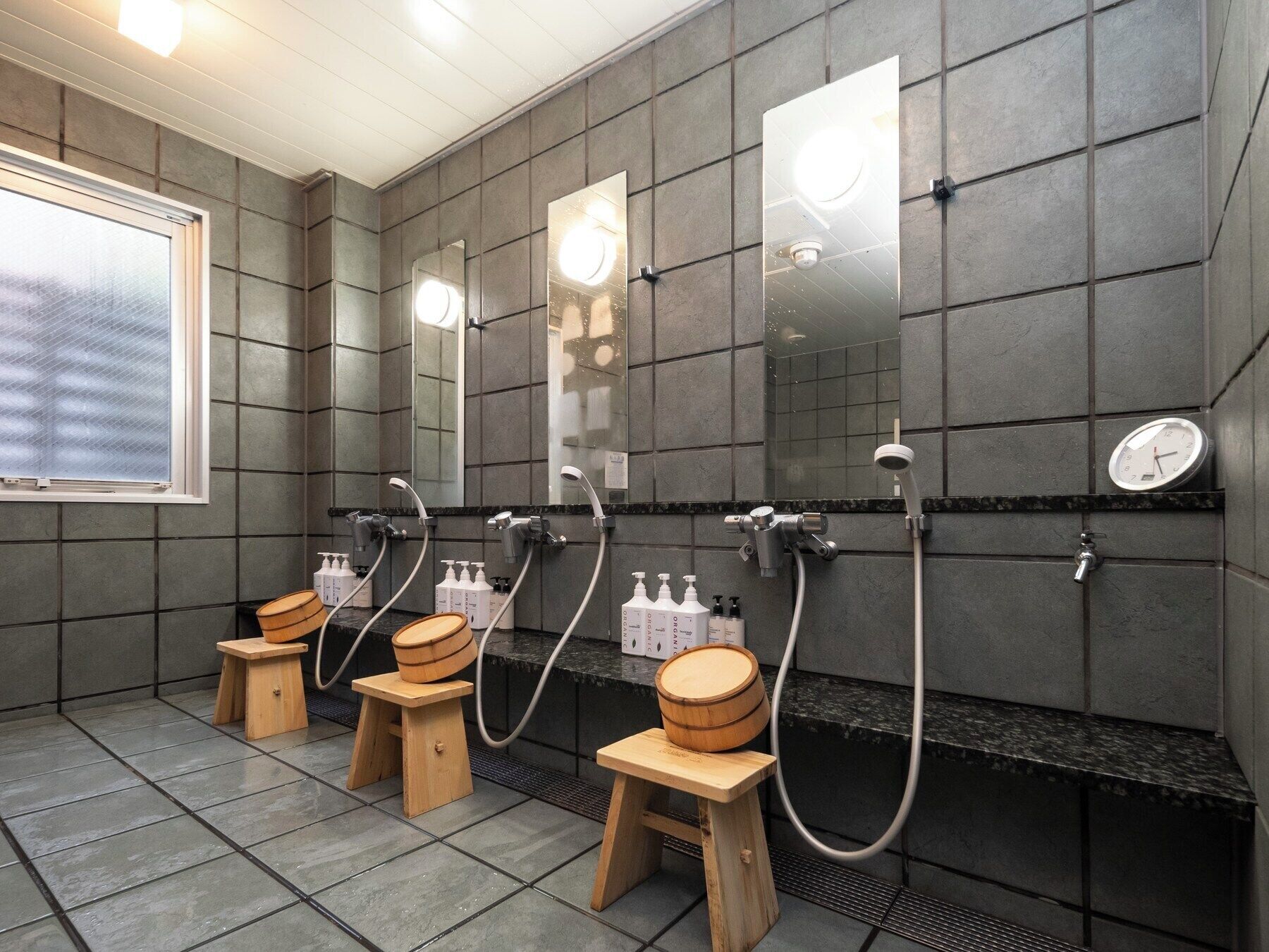 Ein modernes Badezimmer mit mehreren Waschbecken, Spiegeln und Holzschemeln.