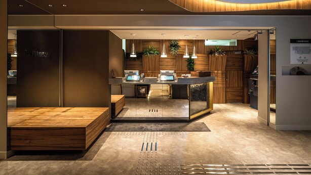 Una cocina moderna con detalles de madera, una isla central, iluminación colgante y un lavamanos a la vista.