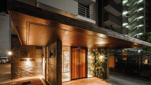 Exterior de un hotel de diseño moderno, con una entrada destacada que incluye una puerta de madera y una reja de metal.
