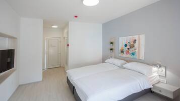 Un dormitorio moderno con una cama grande, mesitas de noche, un televisor de pantalla plana y un cuadro en la pared.