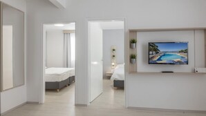 A hotel room with a bed, a TV mounted on the wall, and a view of a pool. - Bellevue Maradiso Village by Aminess  (Orebic)