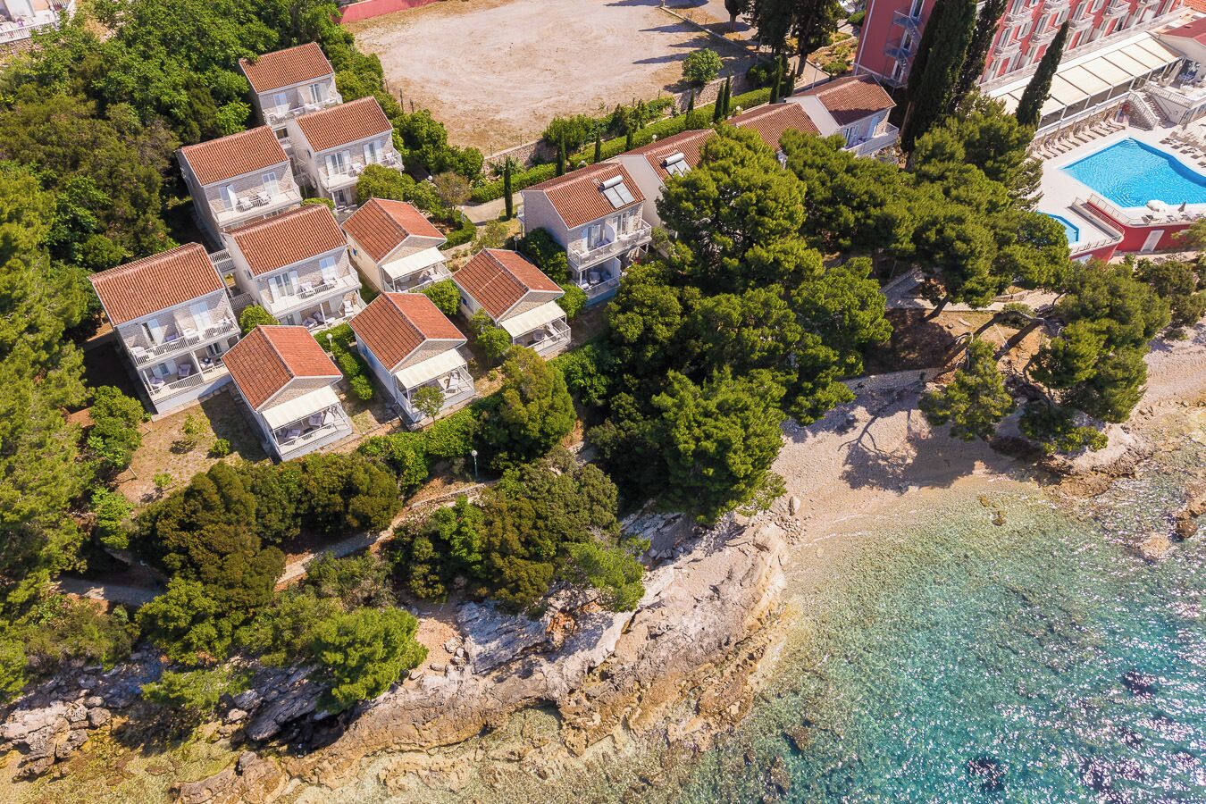 Zona residencial costera con casas, una playa despejada y una piscina.