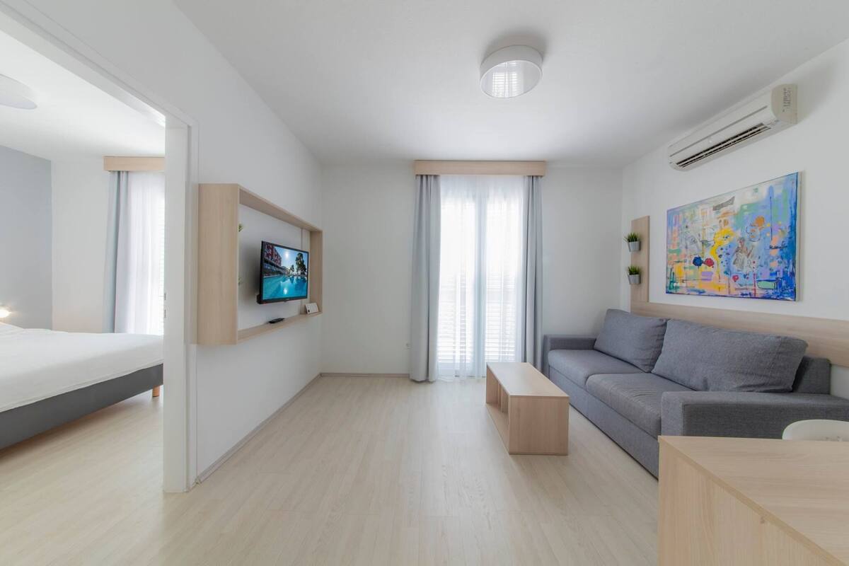 Una habitación de hotel moderna con cama, sofá, televisión, un cuadro y escritorio.